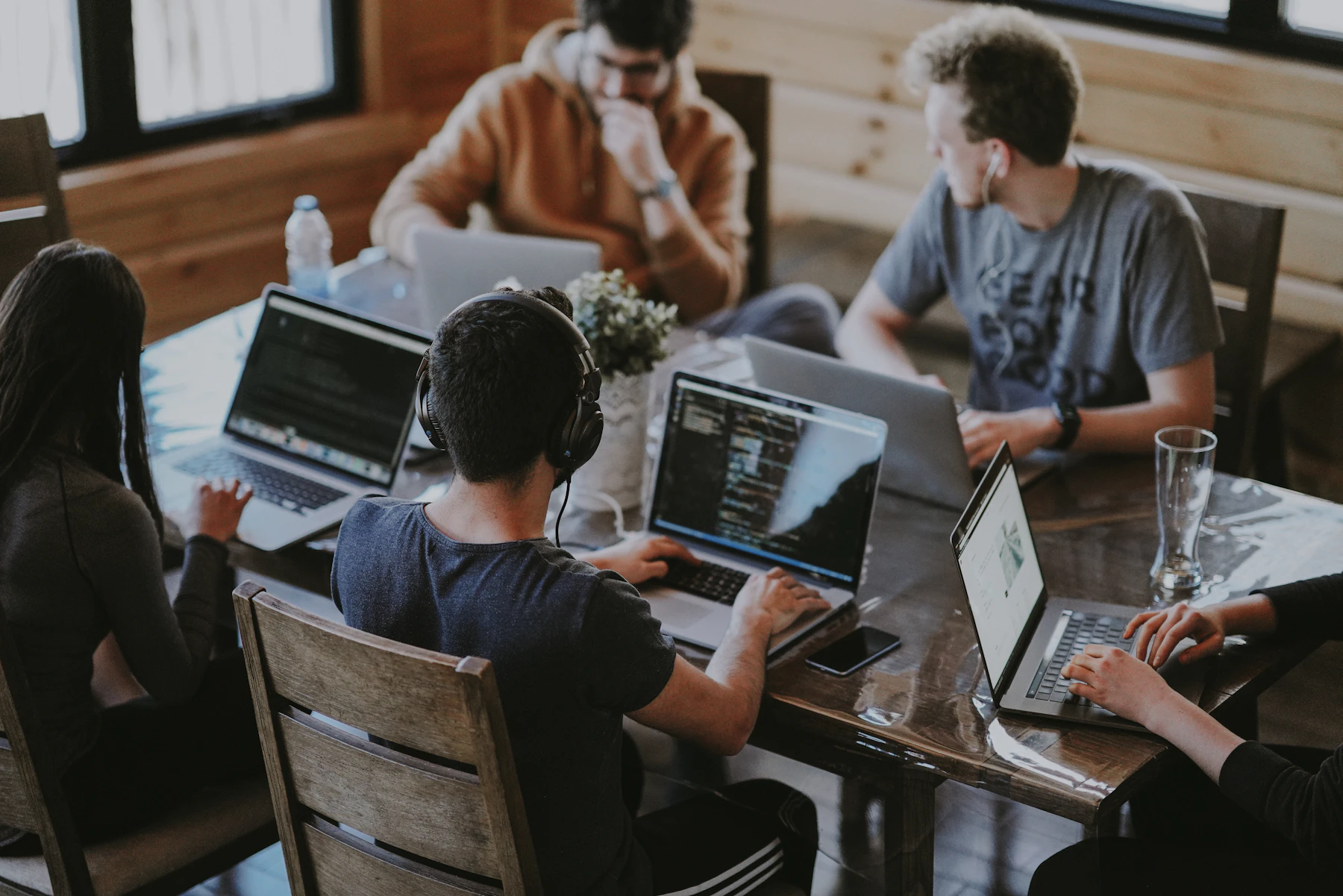 Menschen arbeiten gemeinsam an einem Tisch mit Laptops, Symbolmotiv für Zusammenarbeit